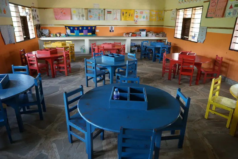 Blick in einen Klassenraum mit blauen und roten Kindertischen
