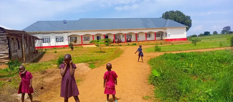 Kinder auf dem Weg zu einem langgestreckten Schulgebäude