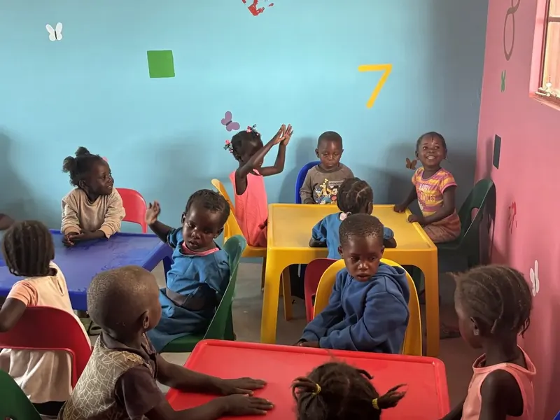 Kleine Kinder sitzen an Tischen in einem bunt gestalteten Klassenraum